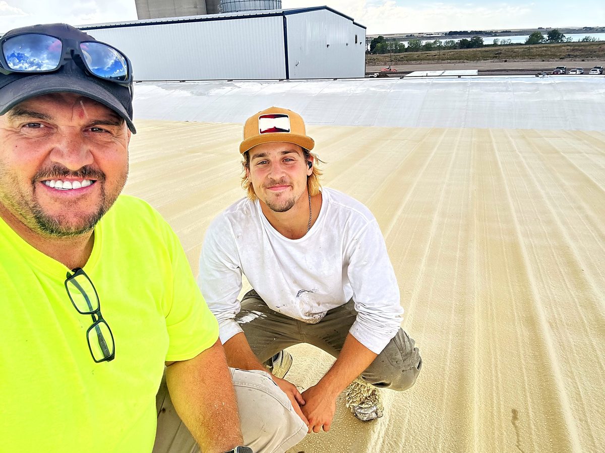 Sam Hostetler, owner of Revive Commercial Roofing, with his son Ben on a freshly coated roof at Driscoll Potatoes, American Falls, Idaho